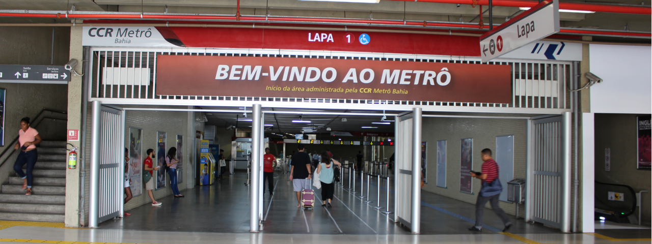 Entrada da estação Lapa do metrô de Salvador com placa “Bem-vindo ao metrô” e passageiros seguindo para as catracas.