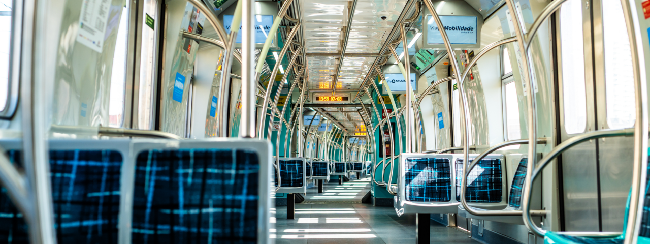 Interior de um trem metropolitano da ViaMobilidade, com assentos vazios e estrutura metálica, mostrando luminosidade natural pelas janelas.