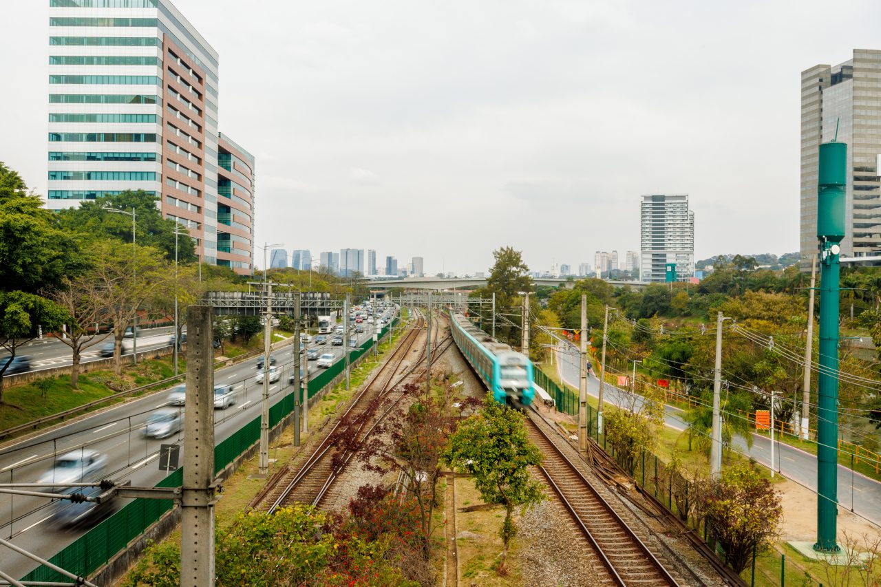 Trem da Linha 9-Esmeralda em movimento ao longo dos trilhos perto do Rio Pinheiros em São Paulo