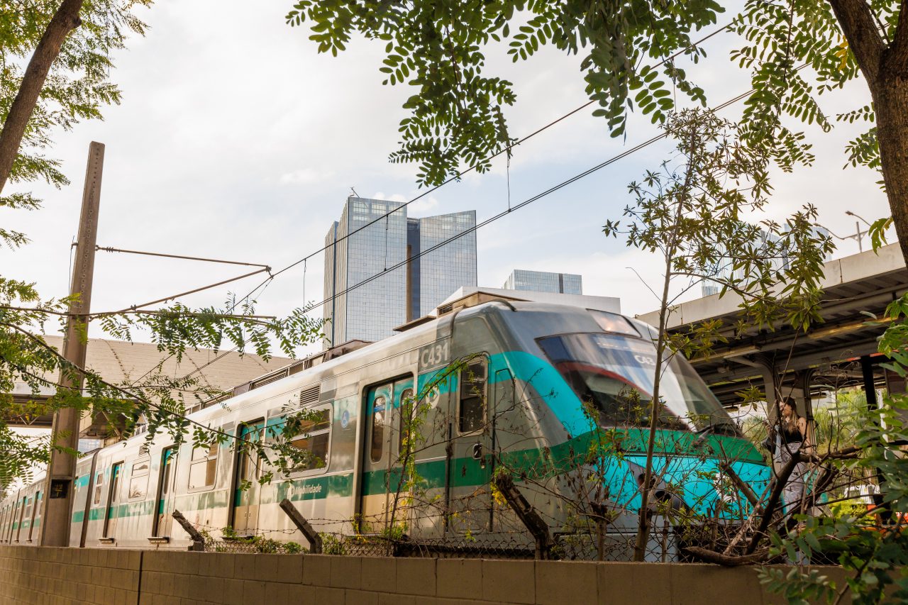 Frente de trem da Linha 9-Esmeralda visto externamente perto da plataforma e sob árvores urbanas