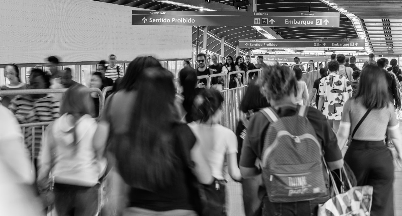 Foto em preto e branco mostrando movimentação de passageiros na área de embarque e acesso da Linha 9-Esmeralda.