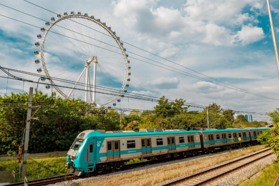 Novo trem da Série 8900 da ViaMobilidade passando com roda-gigante ao fundo, em São Paulo