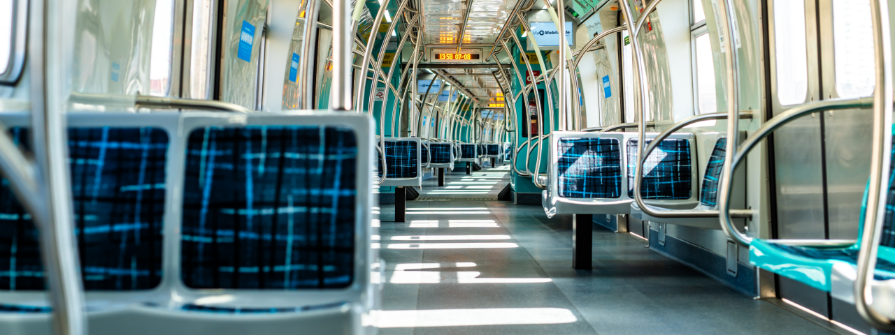 Interior de trem da Linha 9 da ViaMobilidade vazio, com assentos azuis e corredores iluminados pela luz natural.