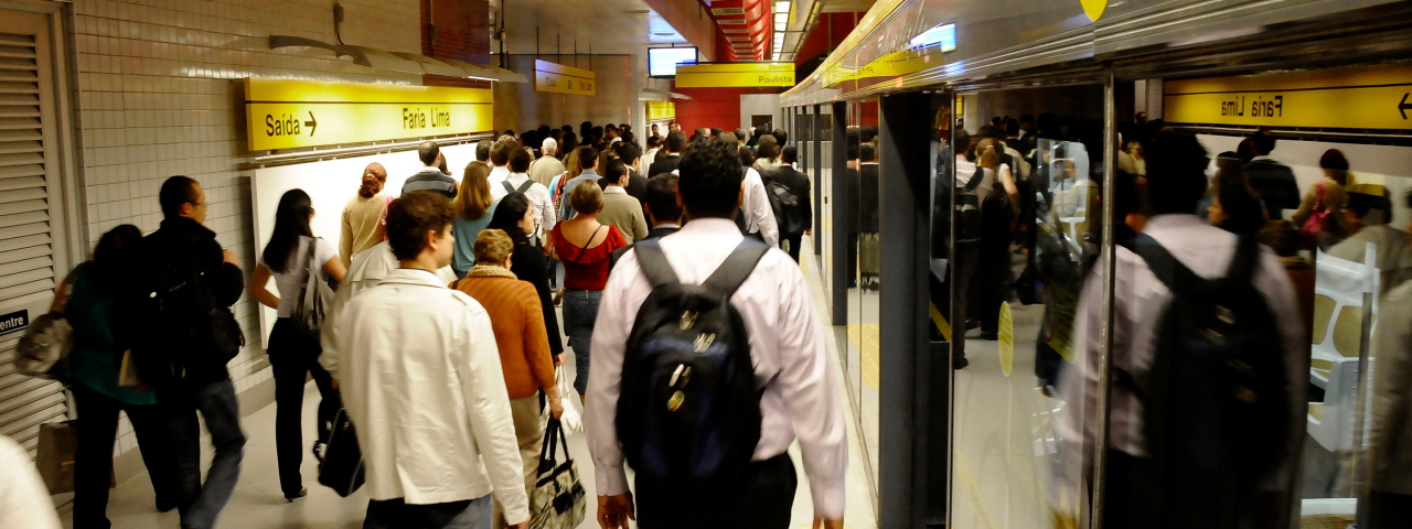 Plataforma movimentada da estação de metrô Faria Lima, com passageiros entrando e saindo dos trens.