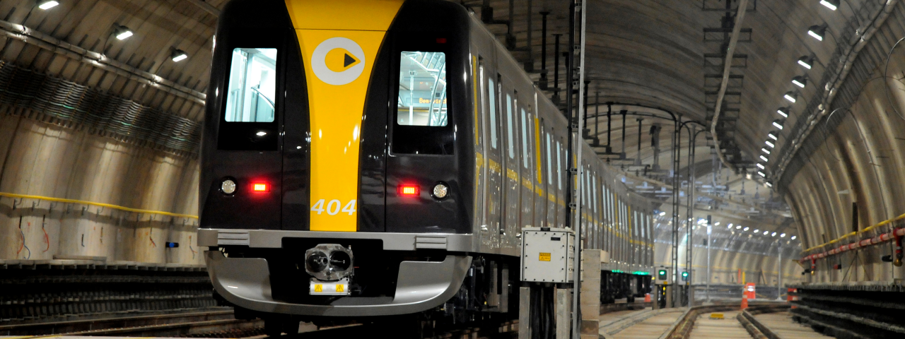 Frontal de trem do metrô com faixa amarela e preta em túnel iluminado, exibindo número 404.
